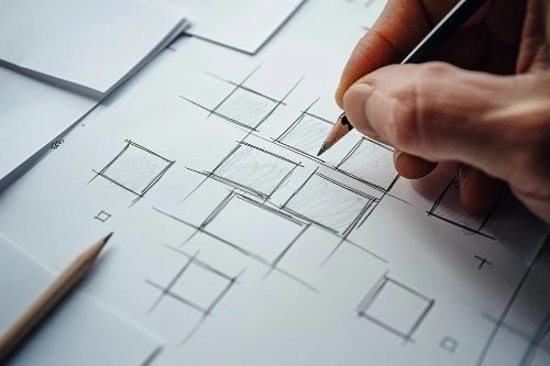 Close-up of a hand drawing a diagram with squares, symbolizing the concept of square root.